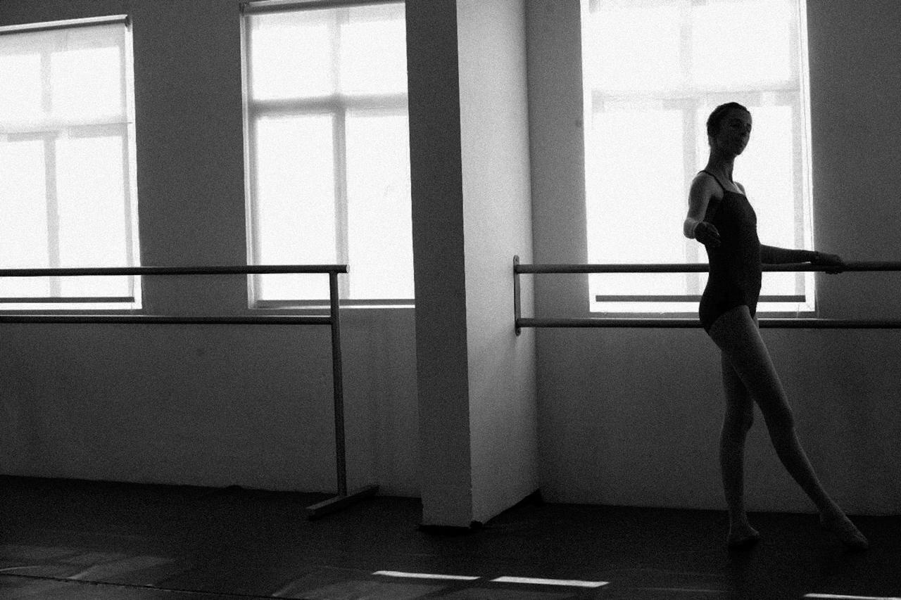Una bailarina junto a la barra, frente a los ventanales del estudio