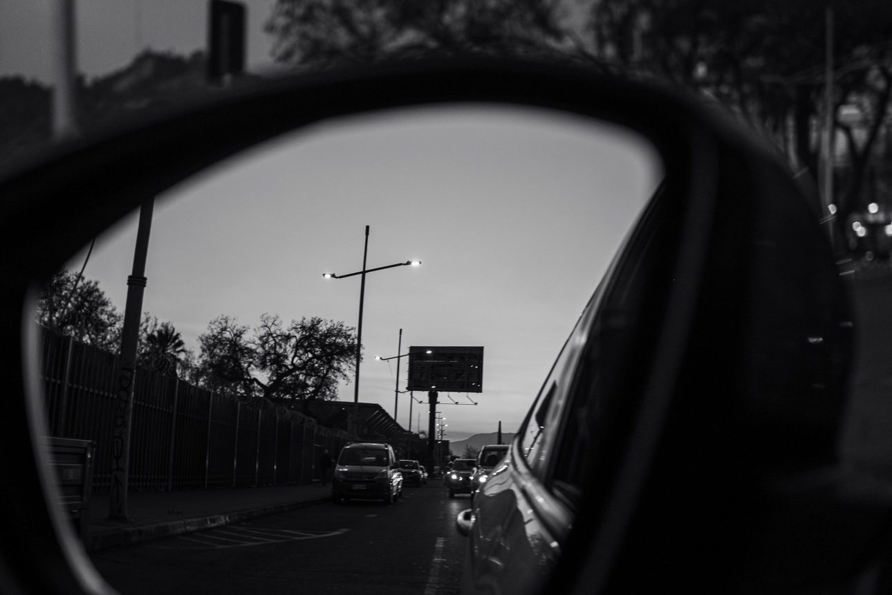 La calle al atardecer vista a través del espejo retrovisor