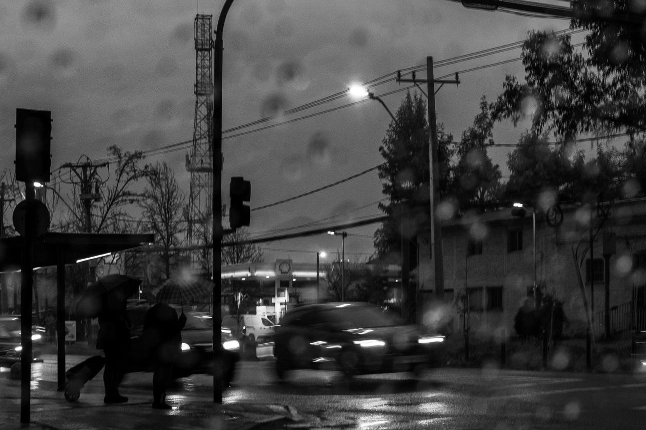 Dos personas con paraguas esperando bajo la lluvia nocturna