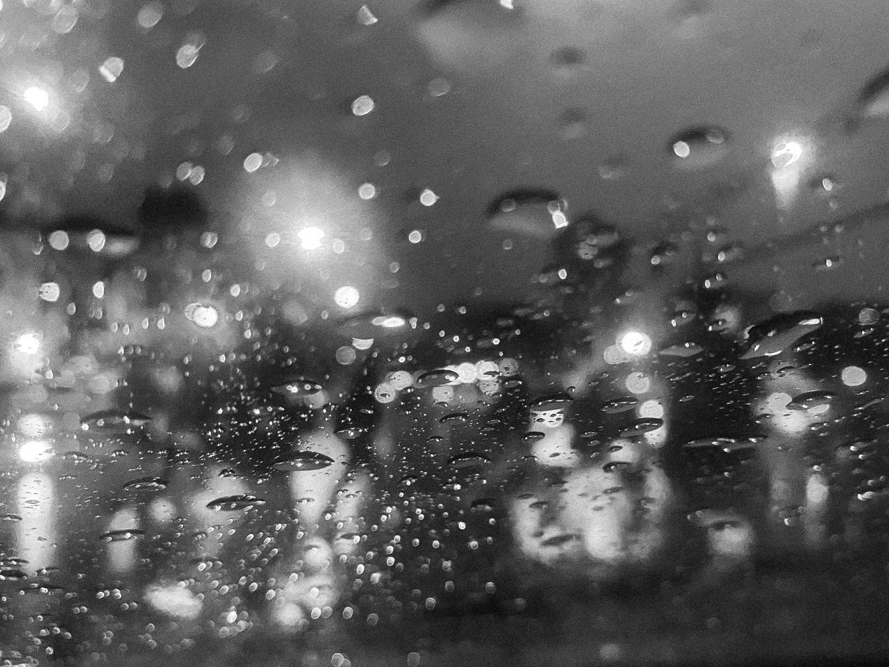 Gotas de lluvia sobre el vidrio, con las luces de la ciudad convertidas en círculos de luz